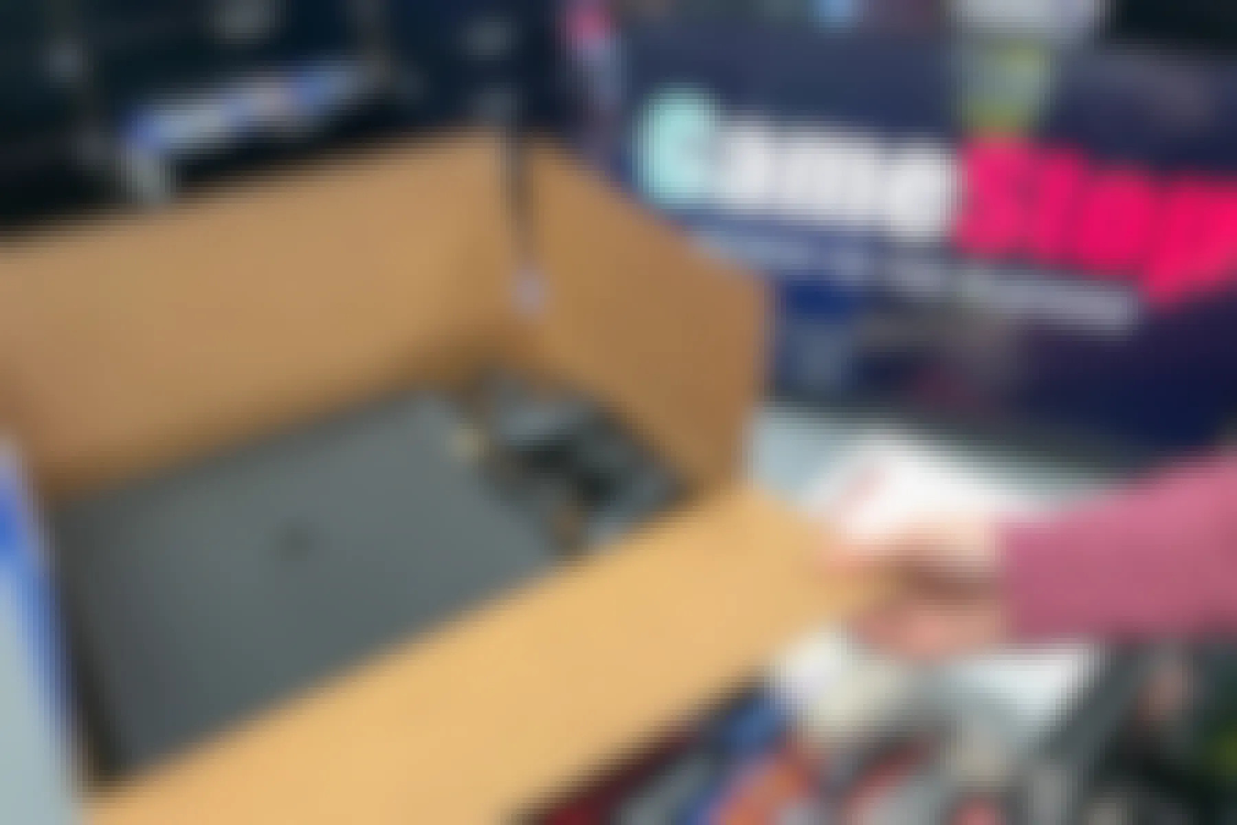 A person holding open a ps4 box sitting on a GameStop counter.