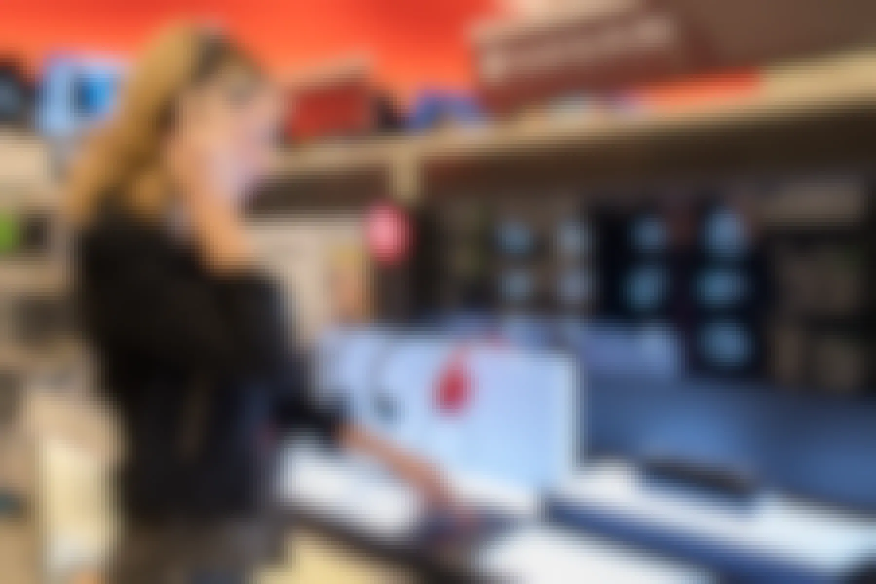 A woman standing at the Beats by Dre display, testing some headphones in the electronics section at Target.