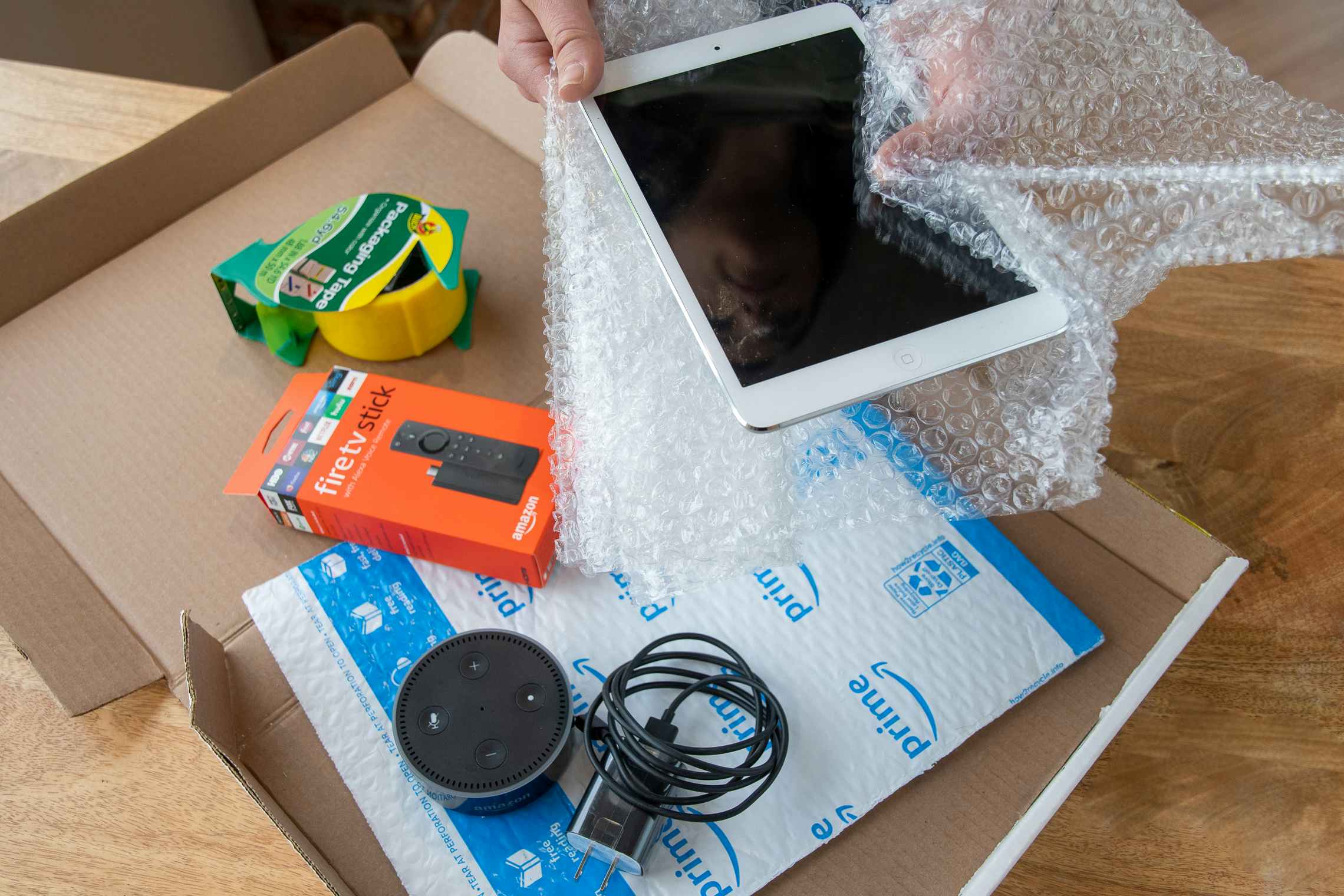 An iPad, Amazon Fire stick, and Amazon Echo dot being boxed up to ship.
