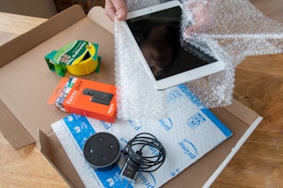 An iPad, Amazon Fire stick, and Amazon Echo dot being boxed up to ship.