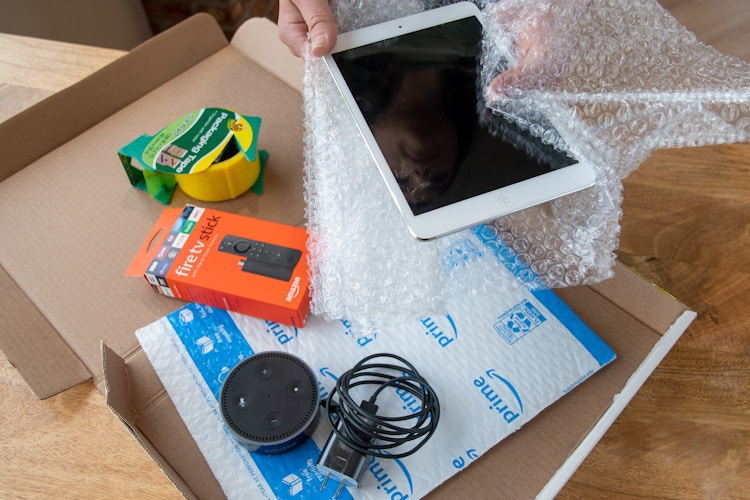 An iPad, Amazon Fire stick, and Amazon Echo dot being boxed up to ship.