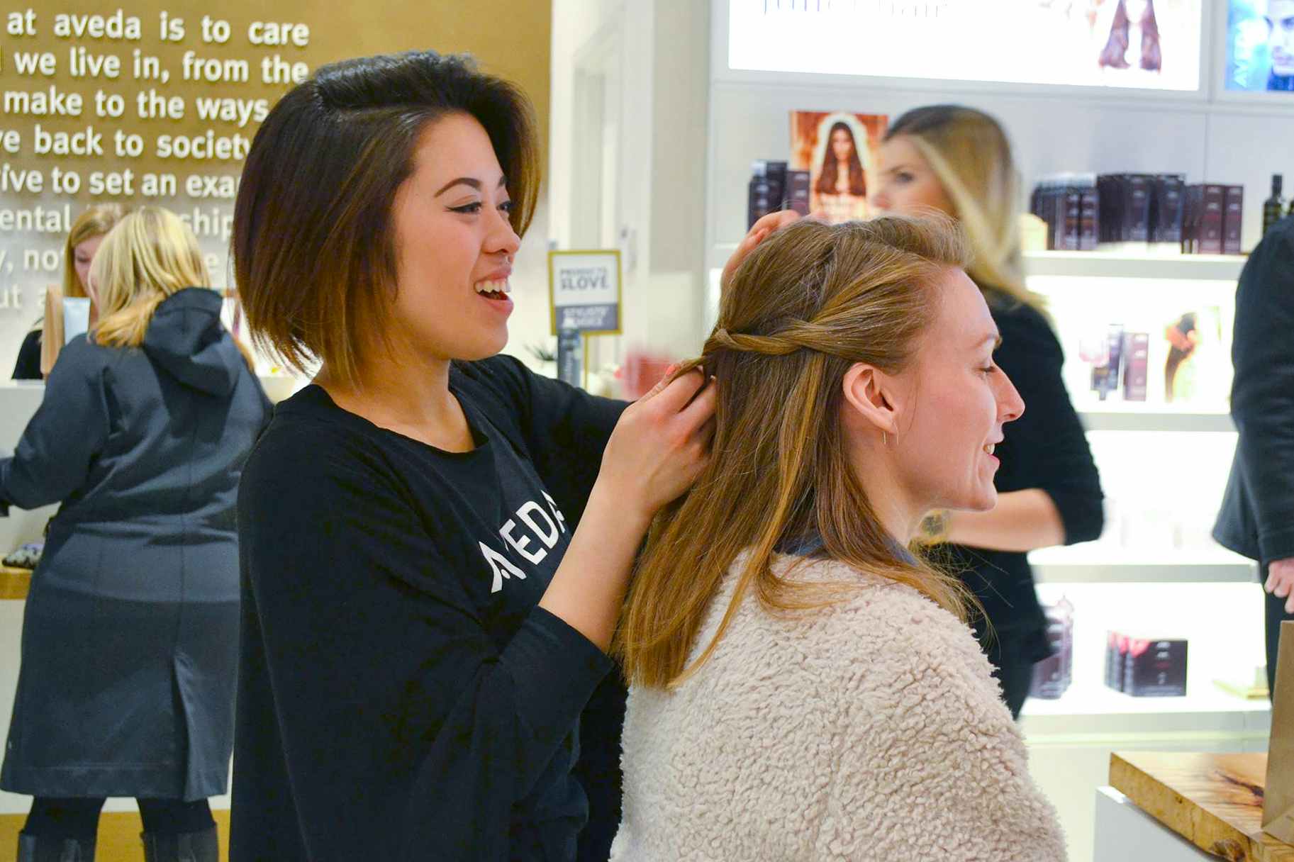 A woman sitting in a salon for a styling session with an Aveda stylist.