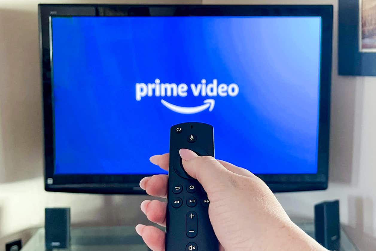 person pointing a remote at a tv with amazon prime video app launching