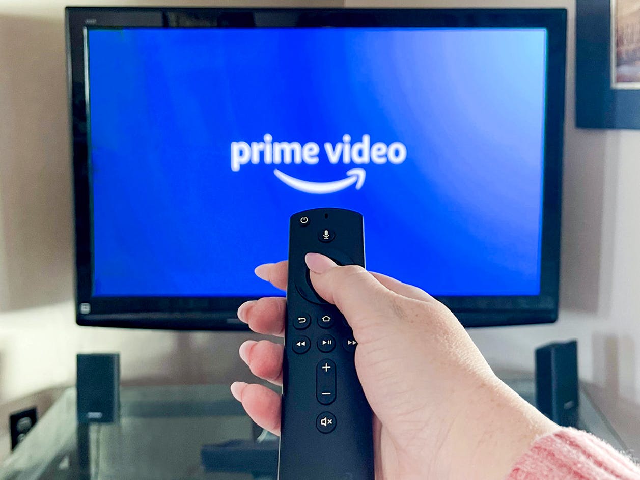 person pointing a remote at a tv with amazon prime video app launching