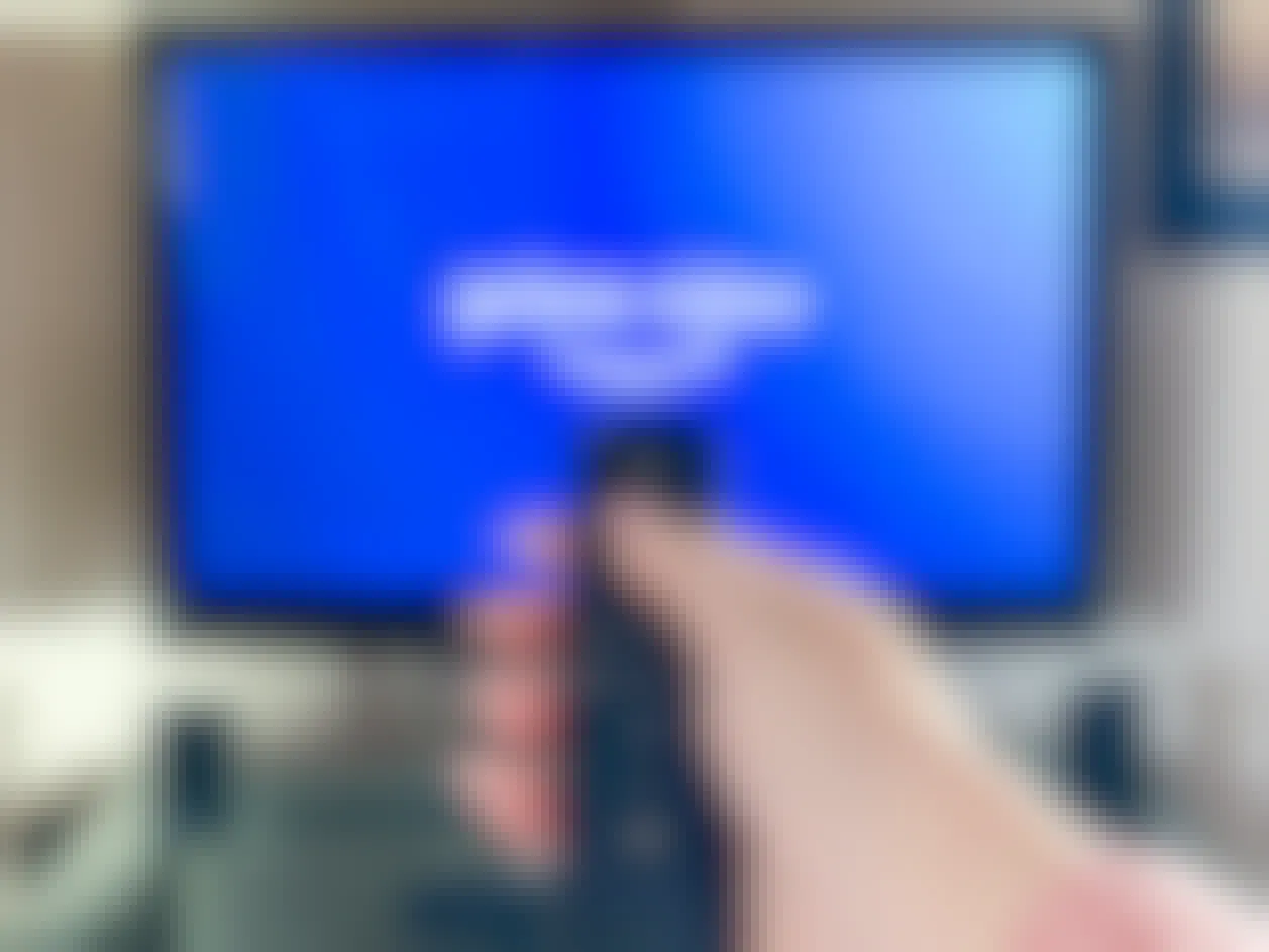 person pointing a remote at a tv with amazon prime video app launching