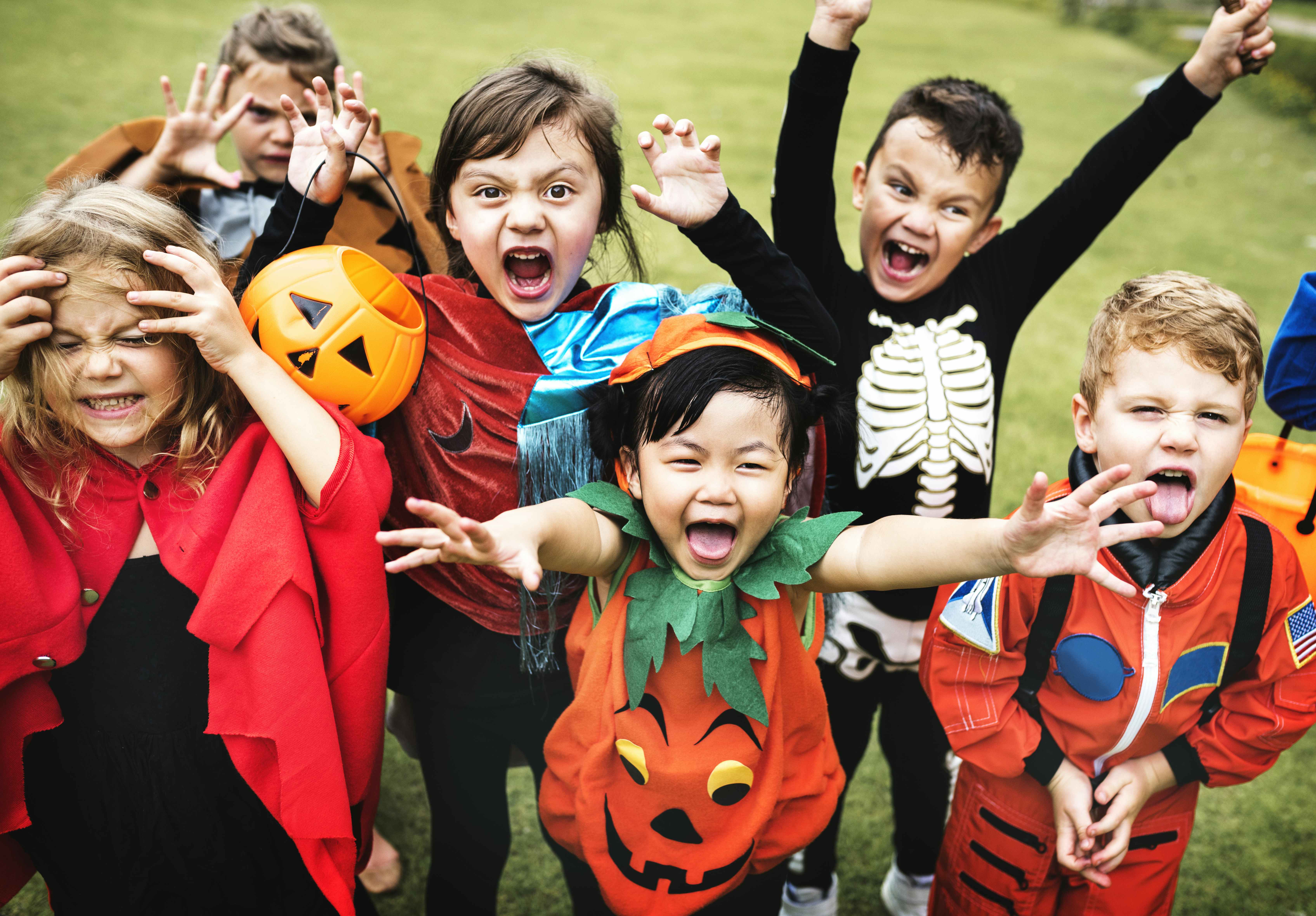 Children excitedly cheering dressed in costumes at a Halloween party.
