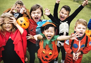 Children excitedly cheering dressed in costumes at a Halloween party.