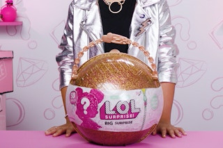 A child standing behind a LOL Surprise bigger surprise toy to be sold on ebay