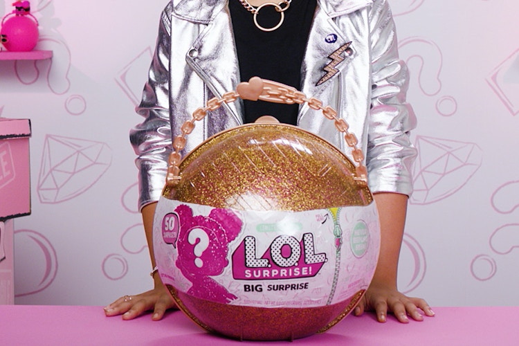 A child standing behind a LOL Surprise bigger surprise toy to be sold on ebay