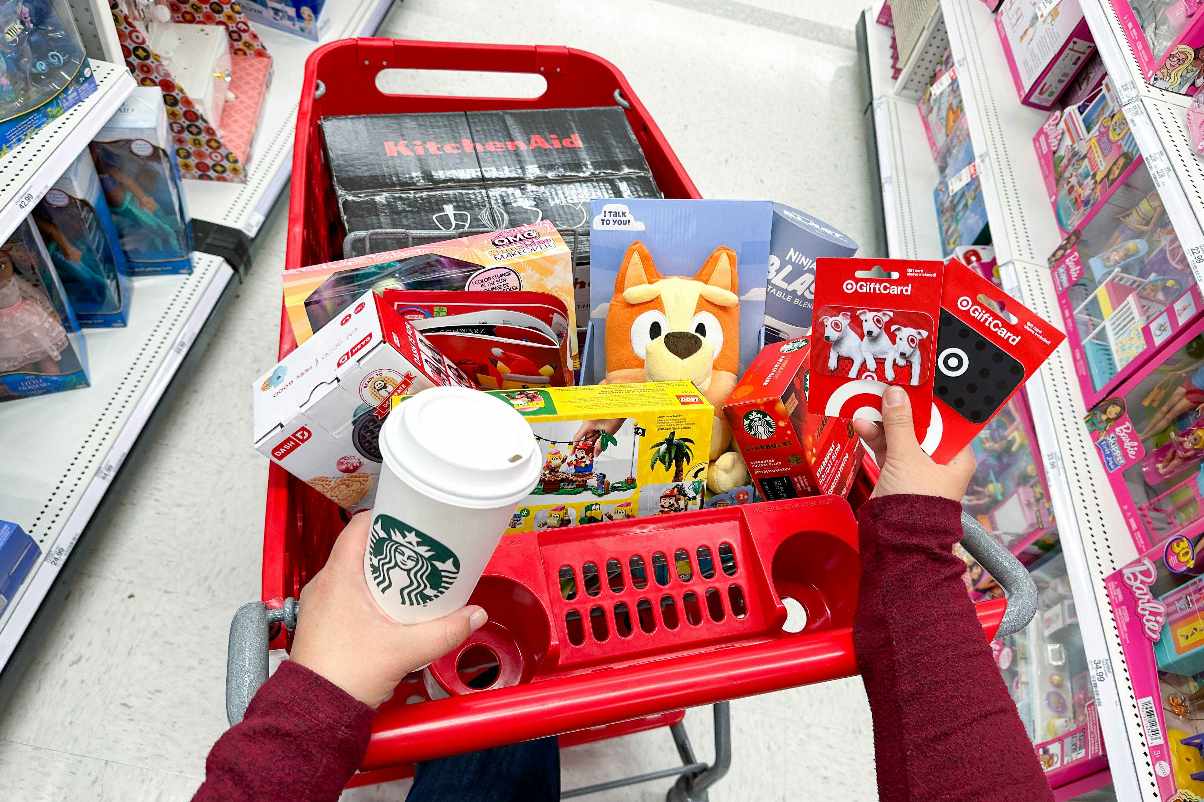 a person holding gift cards near a full target cart 