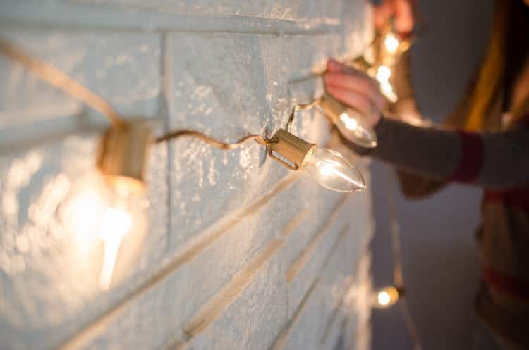 Gold strand of large c9 Christmas light bulbs being hung on the front of a fireplace