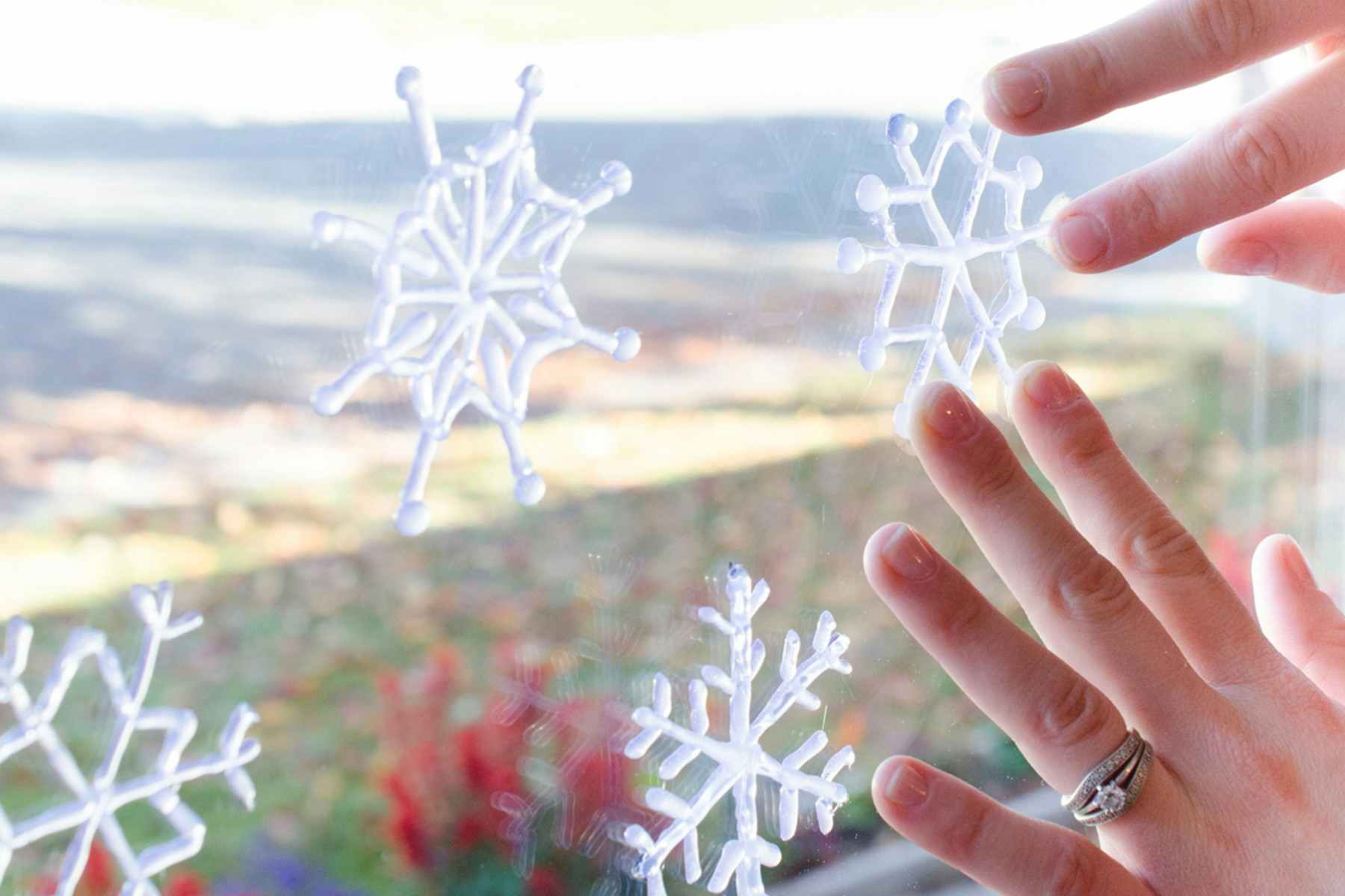 Hot glue snowflakes being attached to a window.