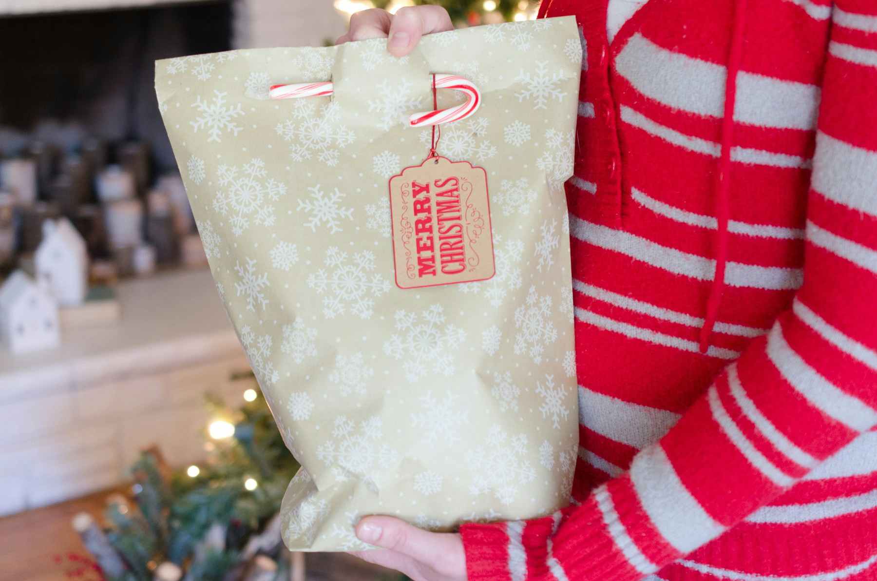 A gift bag made from wrapping paper, secured with a candy cane.