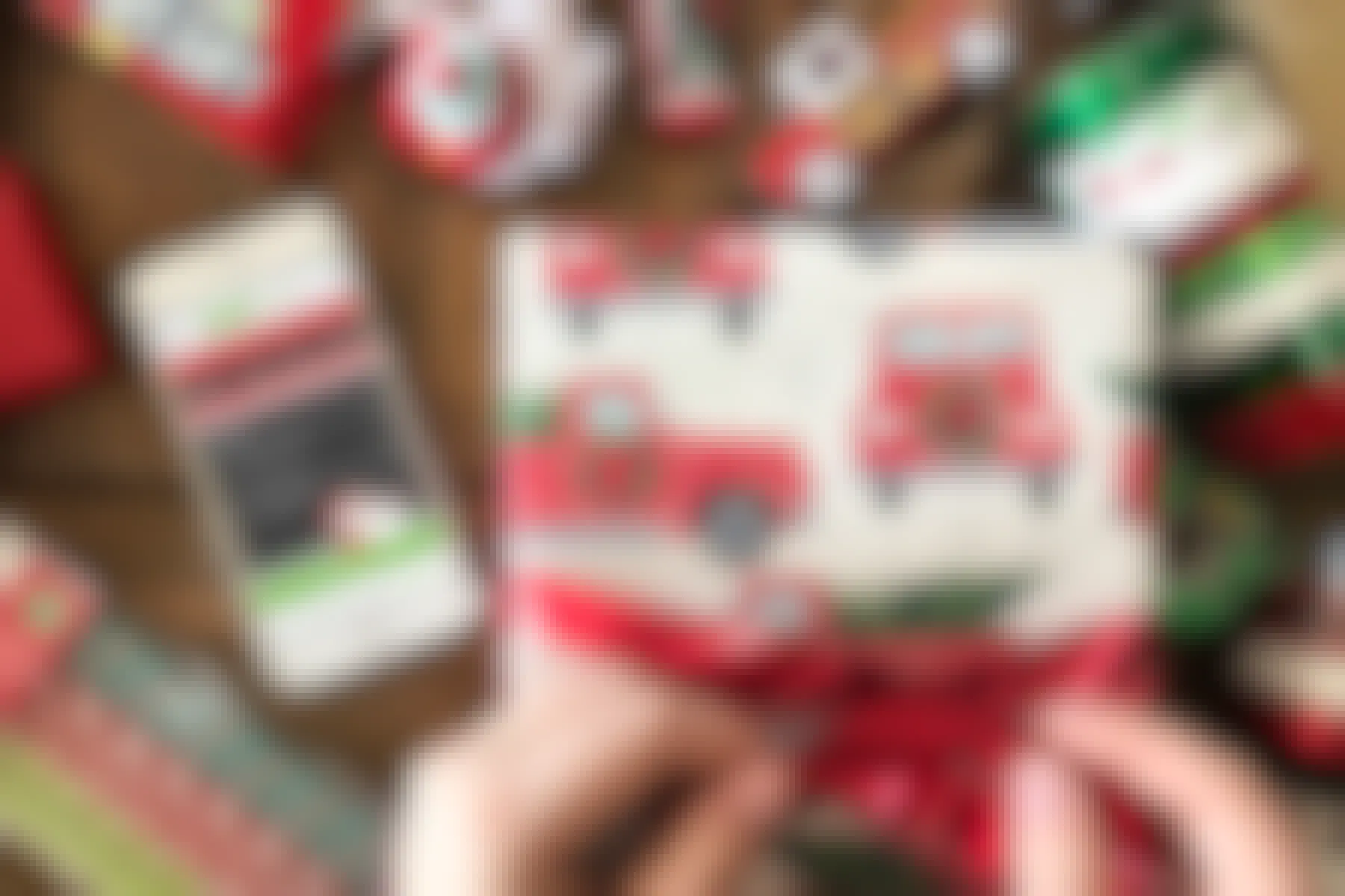 A gift being wrapped with a cell phone beside it displaying the Santas's bag gift tracking app.