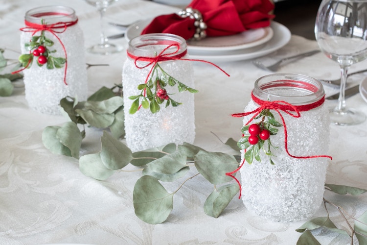 Epsom salt mason jar candle holders in the center of a table, set for a meal.