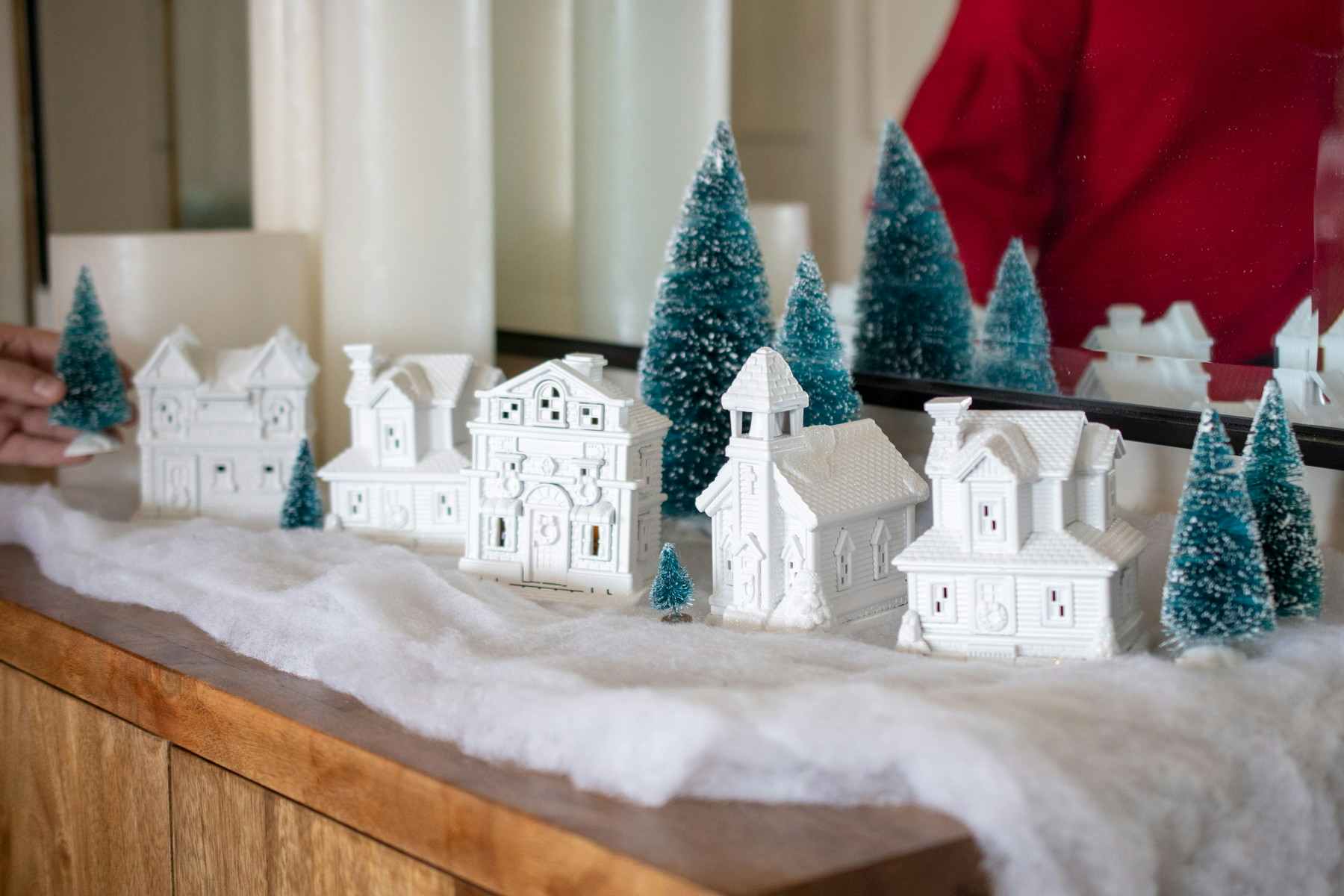White plastic village houses and trees being arranged on a table.
