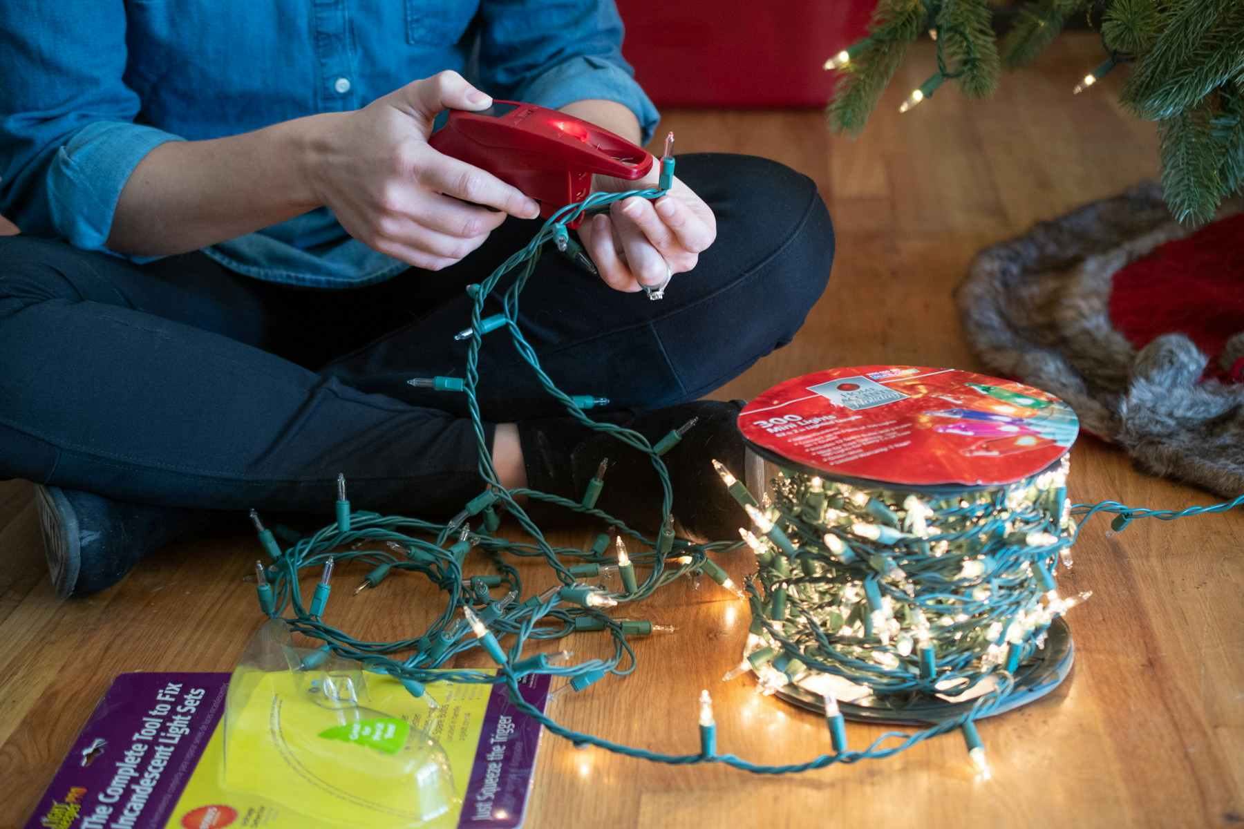 A person using a Christmas light sensor device on a strand of Christmas lights to identify the broken Christmas lights.