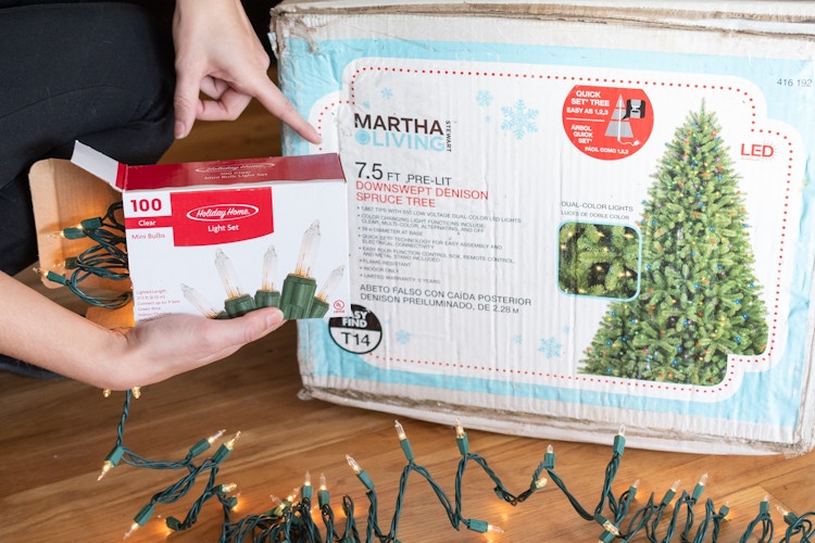 A person holding a box of 100 count Christmas lights, pointing out the height, 7.5 ft, on a Christmas tree box.