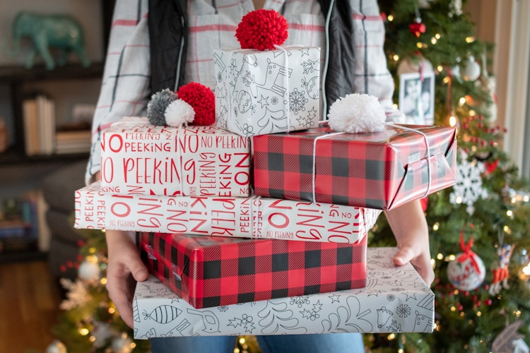 A person holding 5 Christmas wrapped packages 