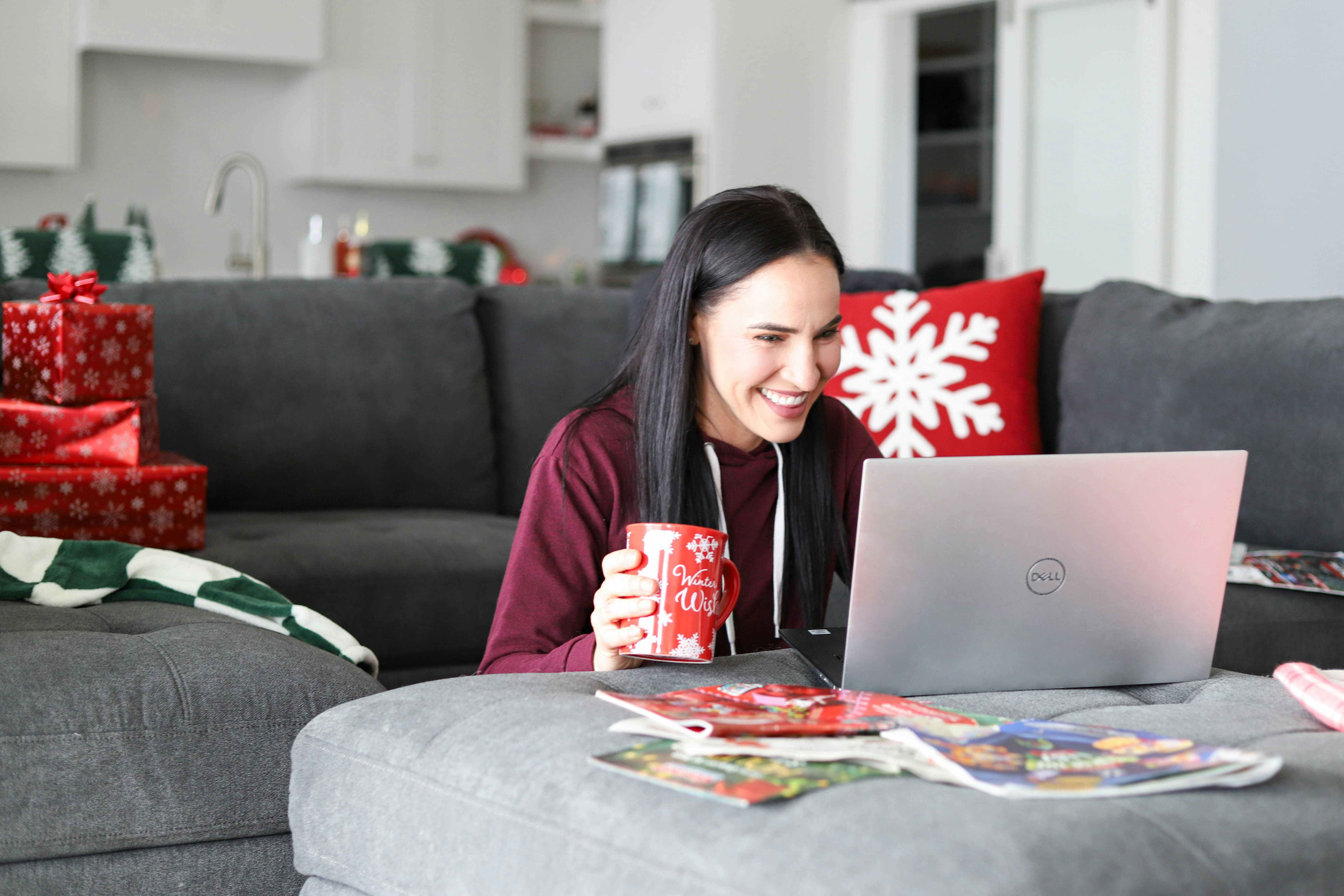 a woman holding a coffee mug and shopping on laptop