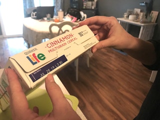 A person holding a box of Life cereal.