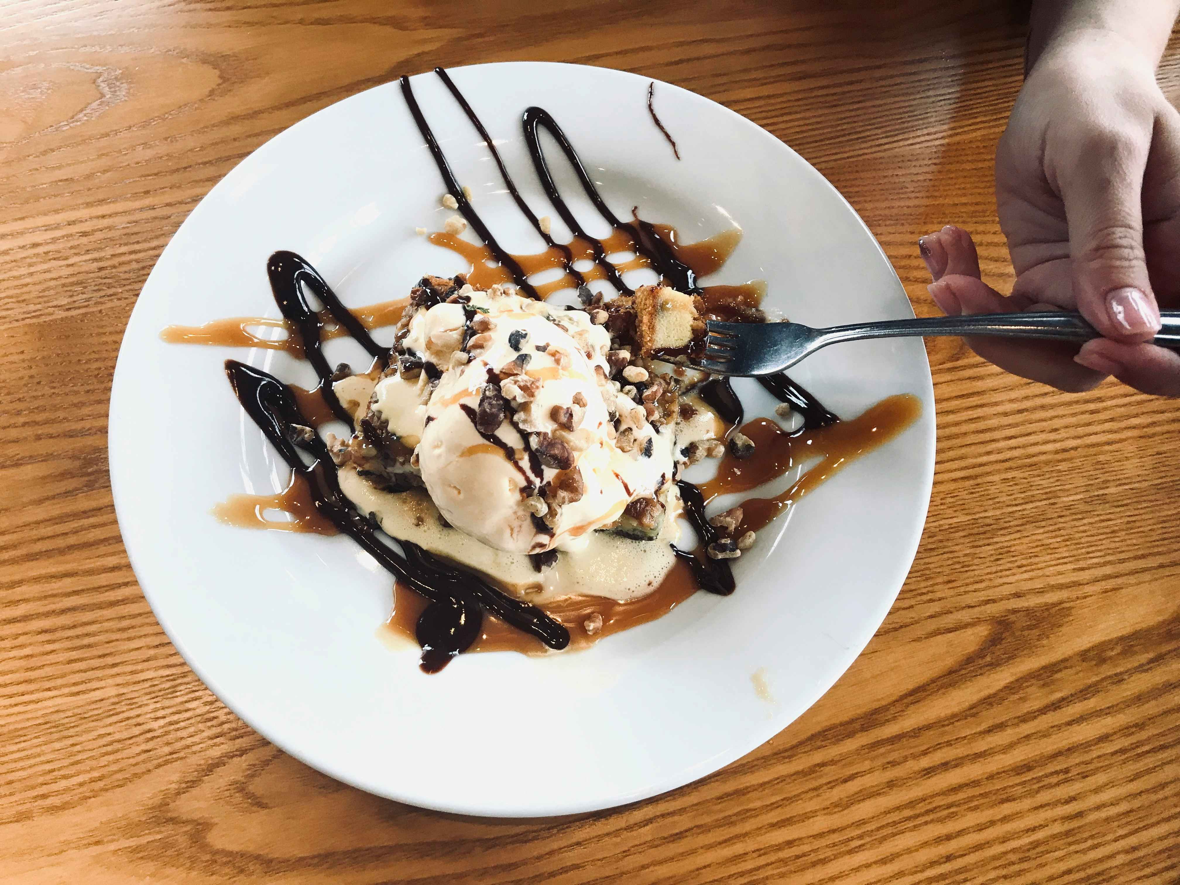 A person's hand using a fork to take some of the plated dessert on the table at Chili's.