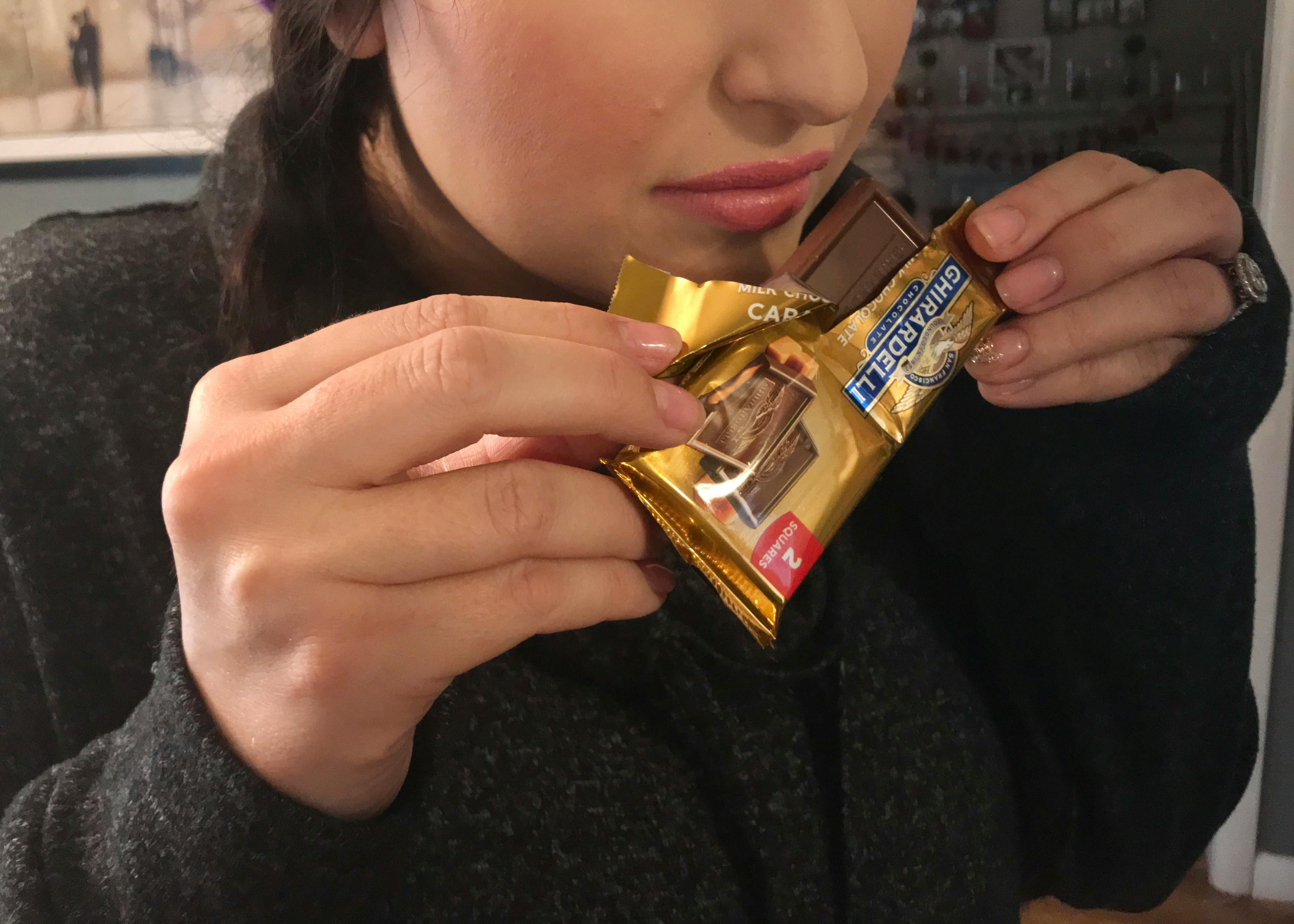 A person smelling a piece of chocolate.