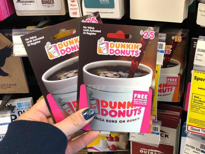 Someone holding some Dunkin gift cards in a store