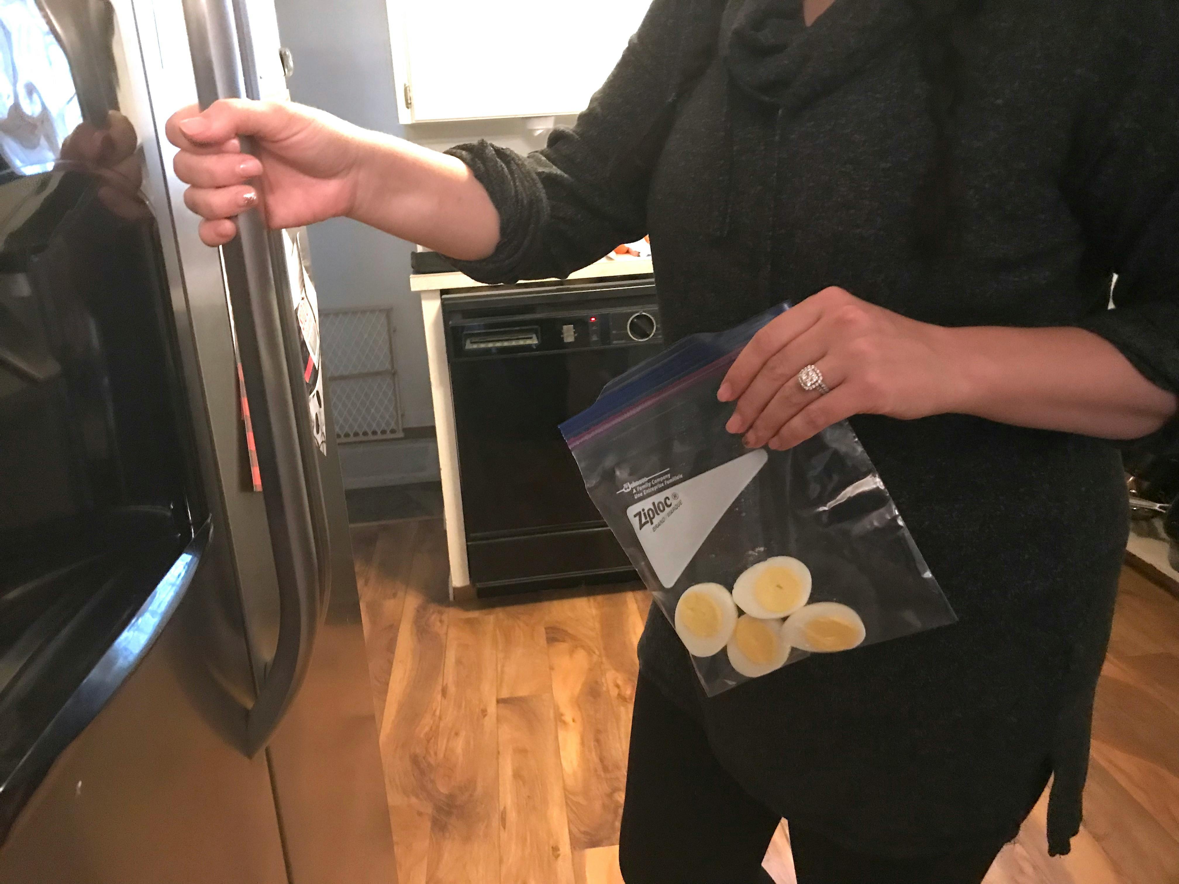 A person putting a zip bag of hardboiled eggs into a freezer.