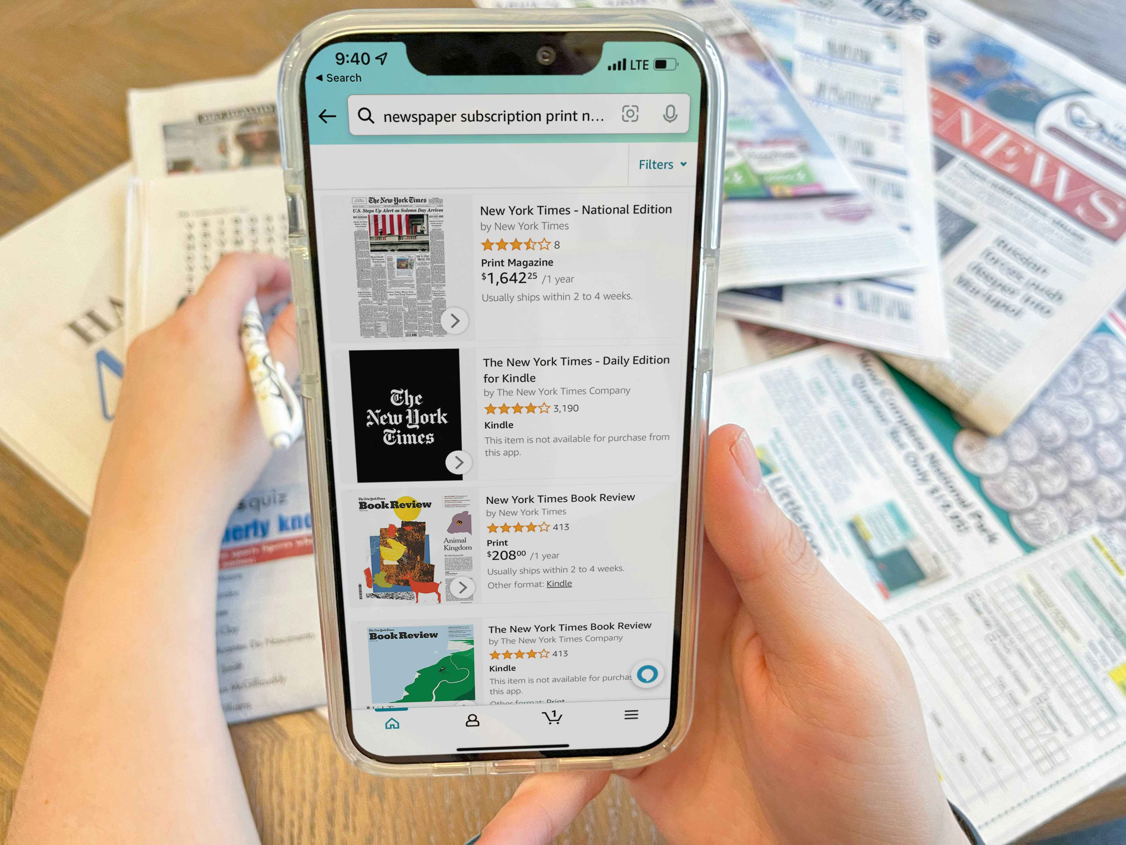 a person holding cellphone with amazon newspaper subscription