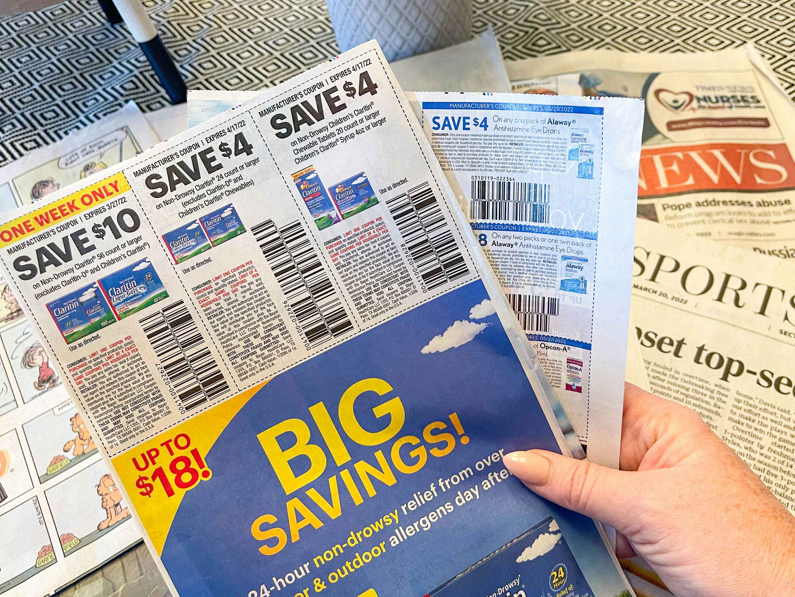a person pulling coupon inset out of newspaper