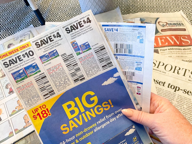 a person pulling coupon inset out of newspaper