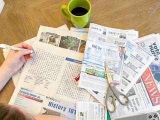 a person doing the crossword puzzle in newspaper