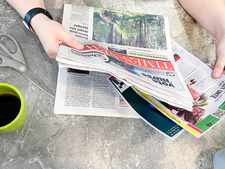 a person pulling coupon inset out of newspaper