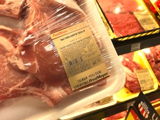 A person holding a package of pork chops.