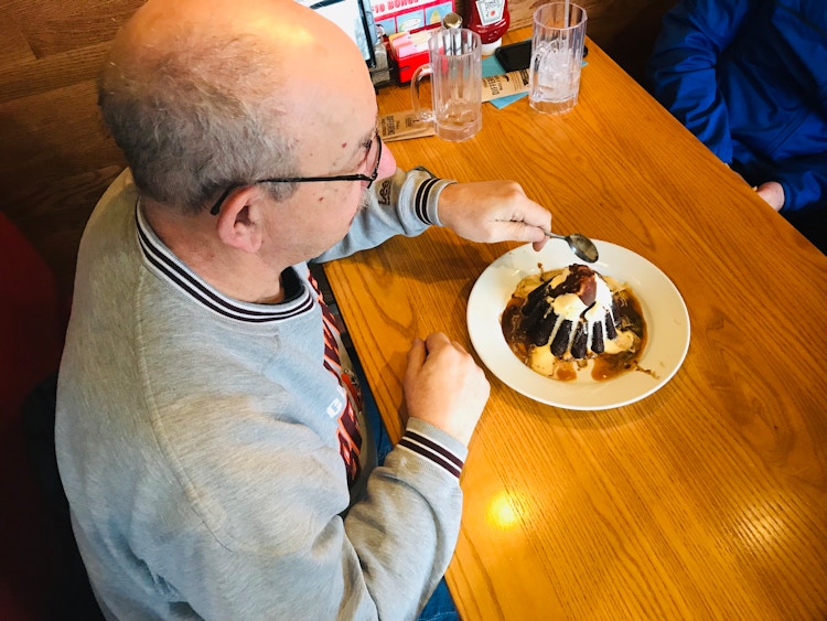A senior sitting at a booth in Chili's, about to start eating a dessert.