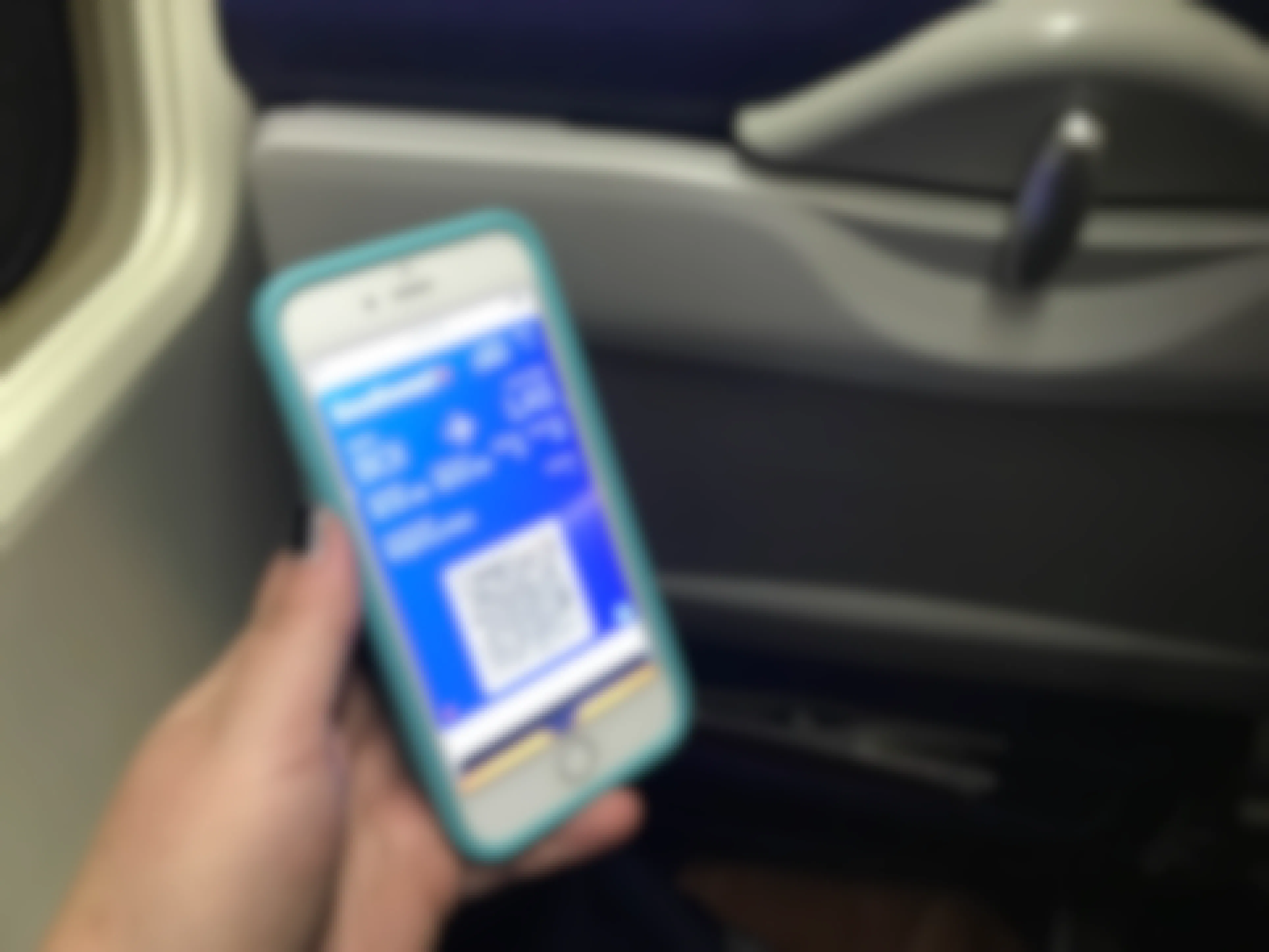 someone holding a phone with ticket on it on airplane
