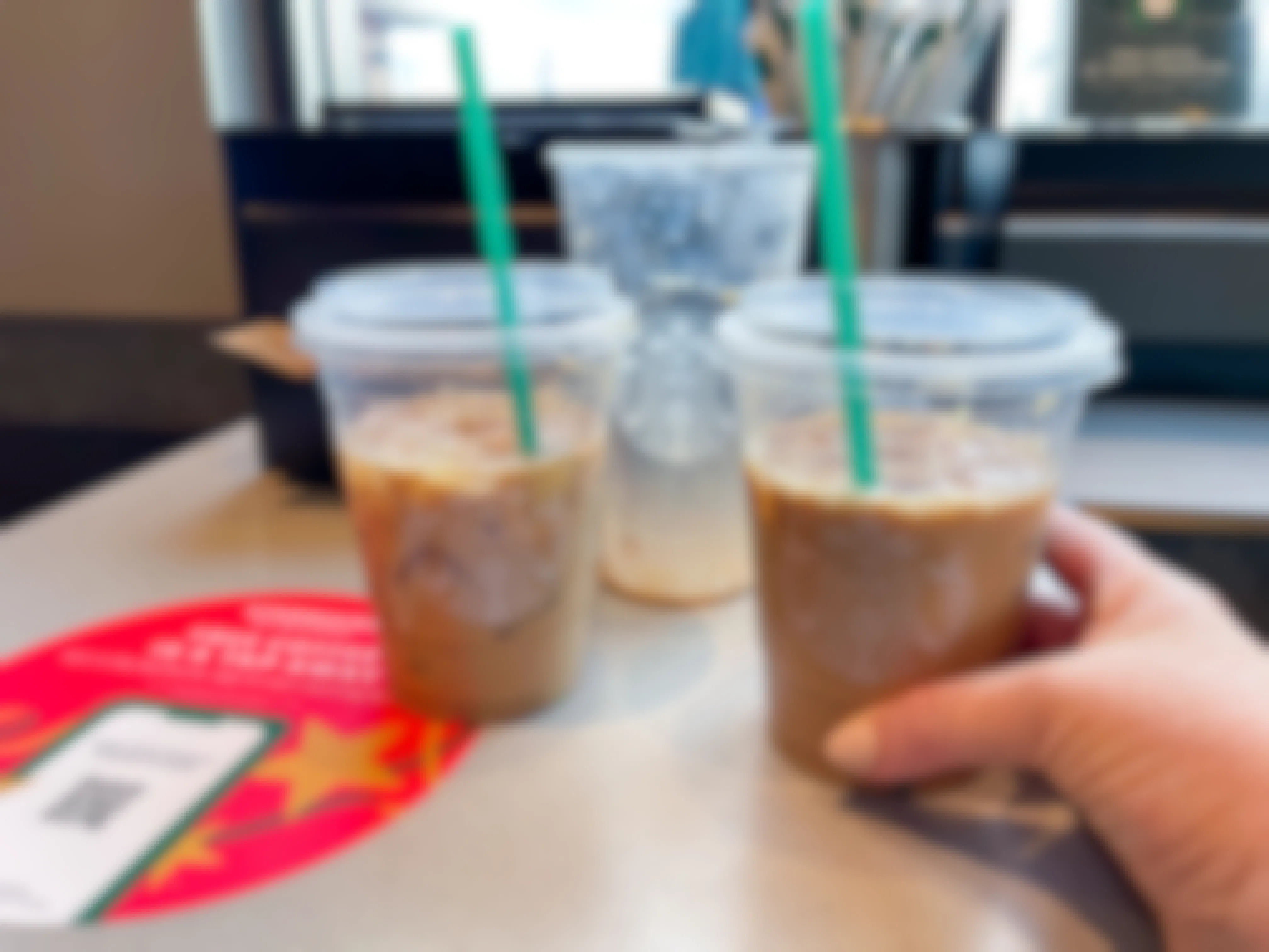 venti iced sugar cookie almond milk latte split into two cups with hand