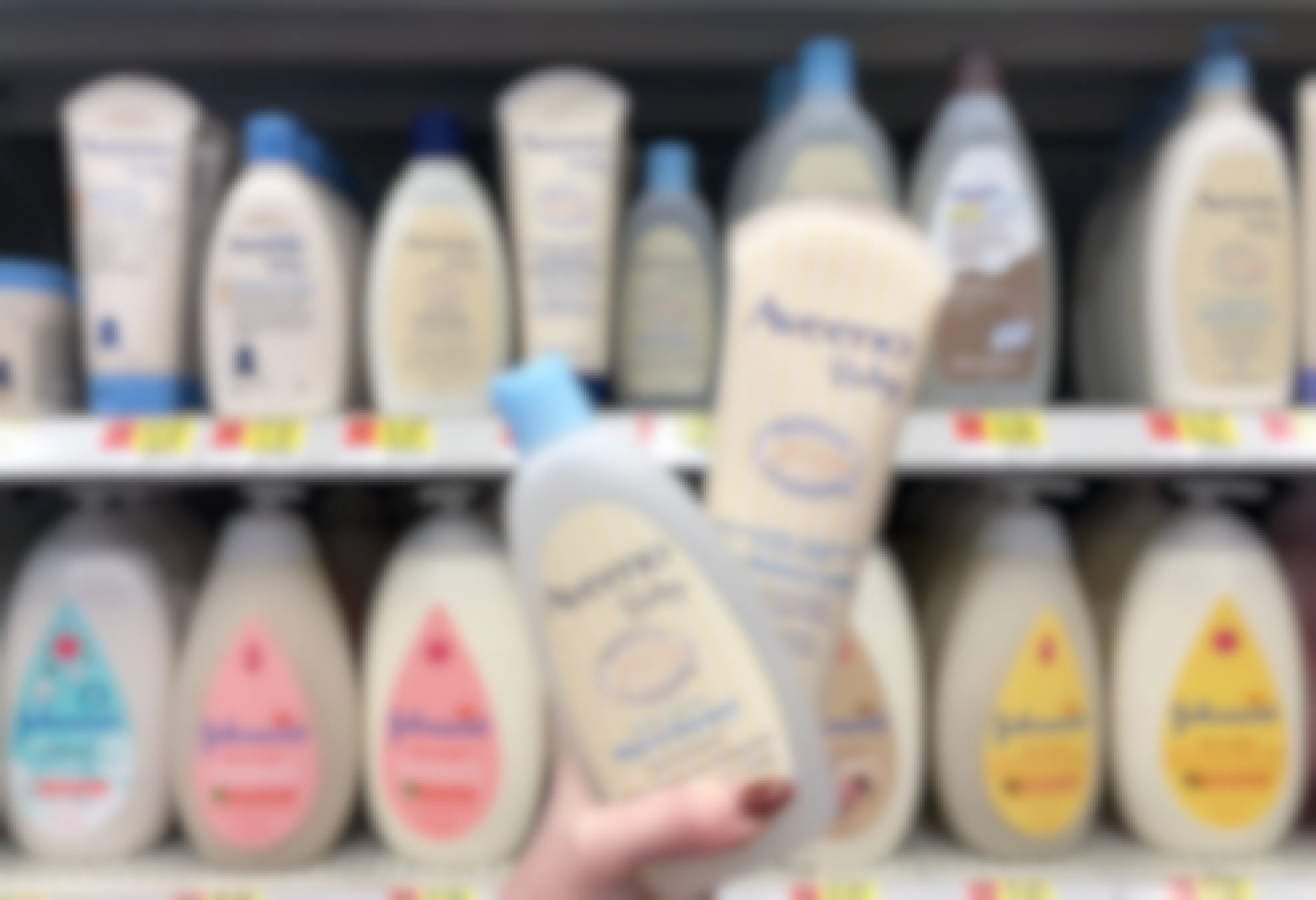 a person holding two bottles of Aveeno baby body wash in front a a baby product aisle. 