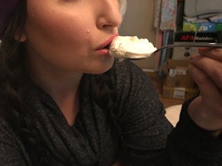 A person taking a bite of yogurt.