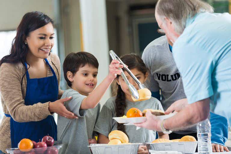 family volunteering by serving in a soup kitchen