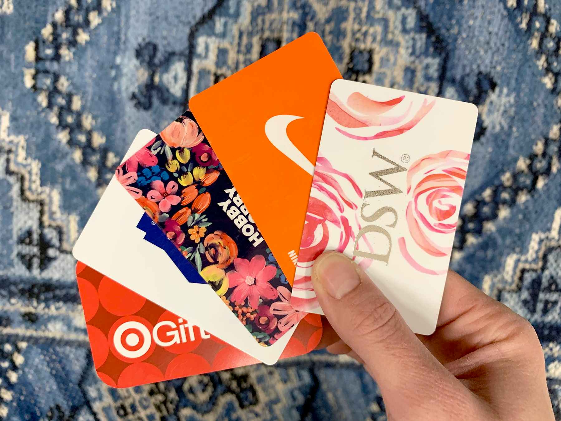 A person holding gift cards for Target, Lowe's, Nike, DSW, and Hobby Lobby.