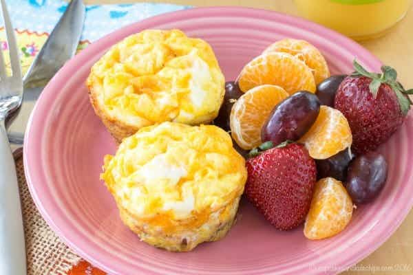 Egg muffins next to a mixed fruit salad on a pink plate