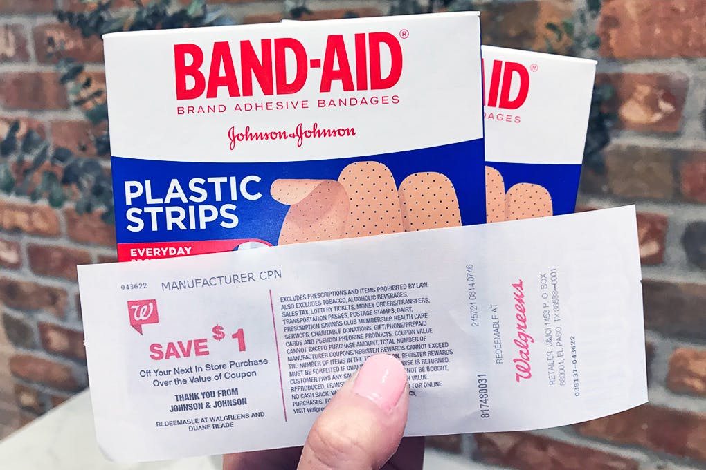 Someone holding some boxes of Band Aids with a catalina coupon from Walgreens