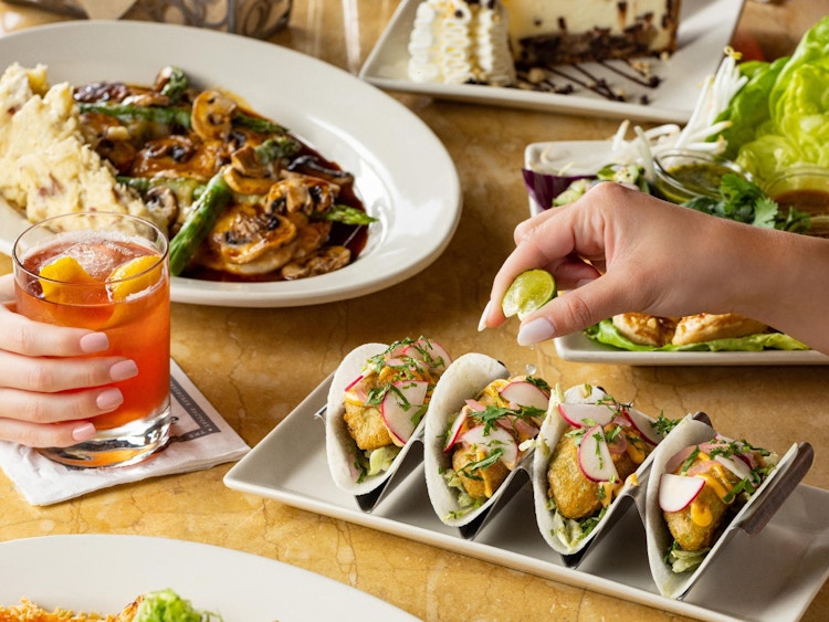 a hand squeezing a lime on taco at the cheesecake factory 
