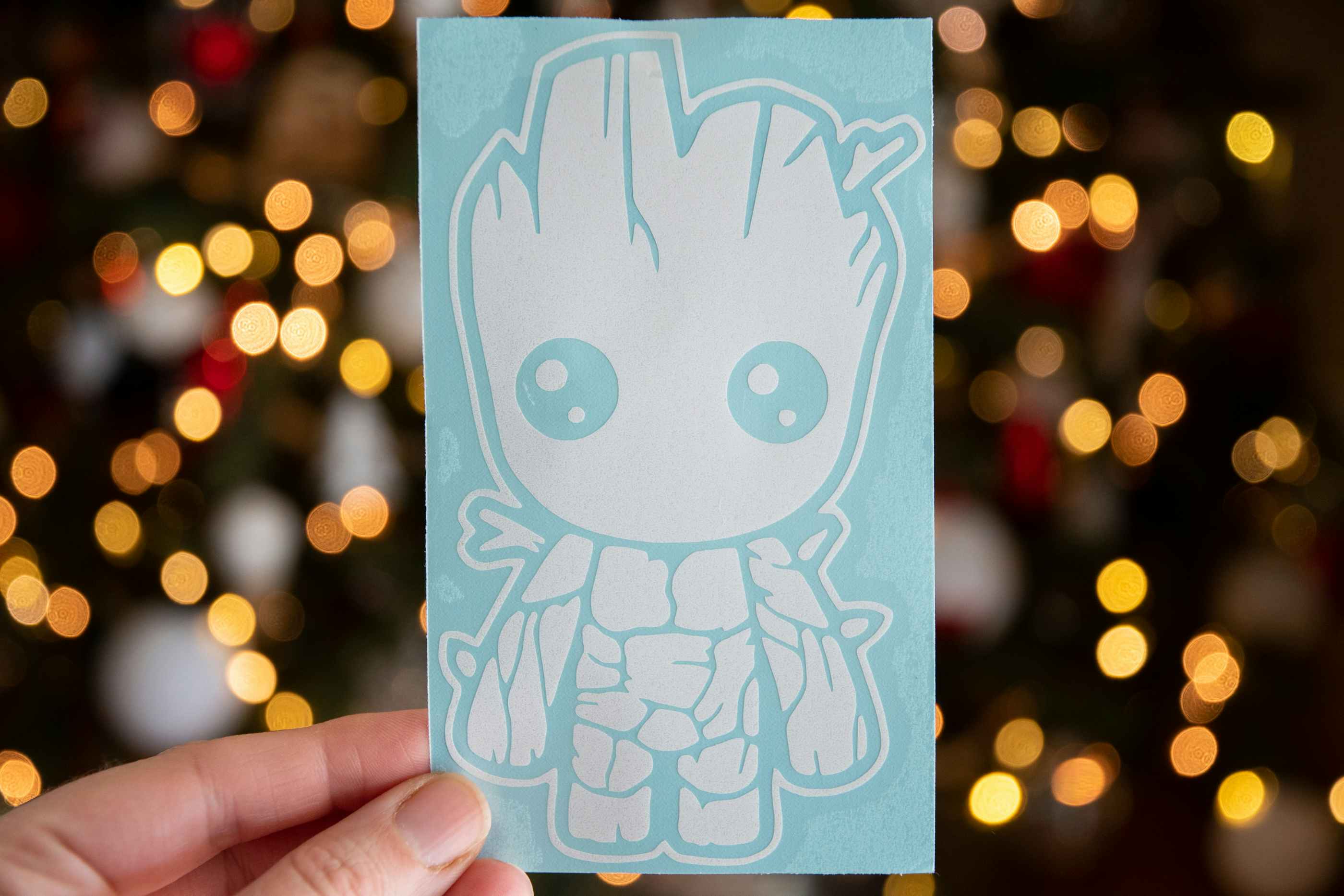 A person holding up a baby groot vinyl sticker