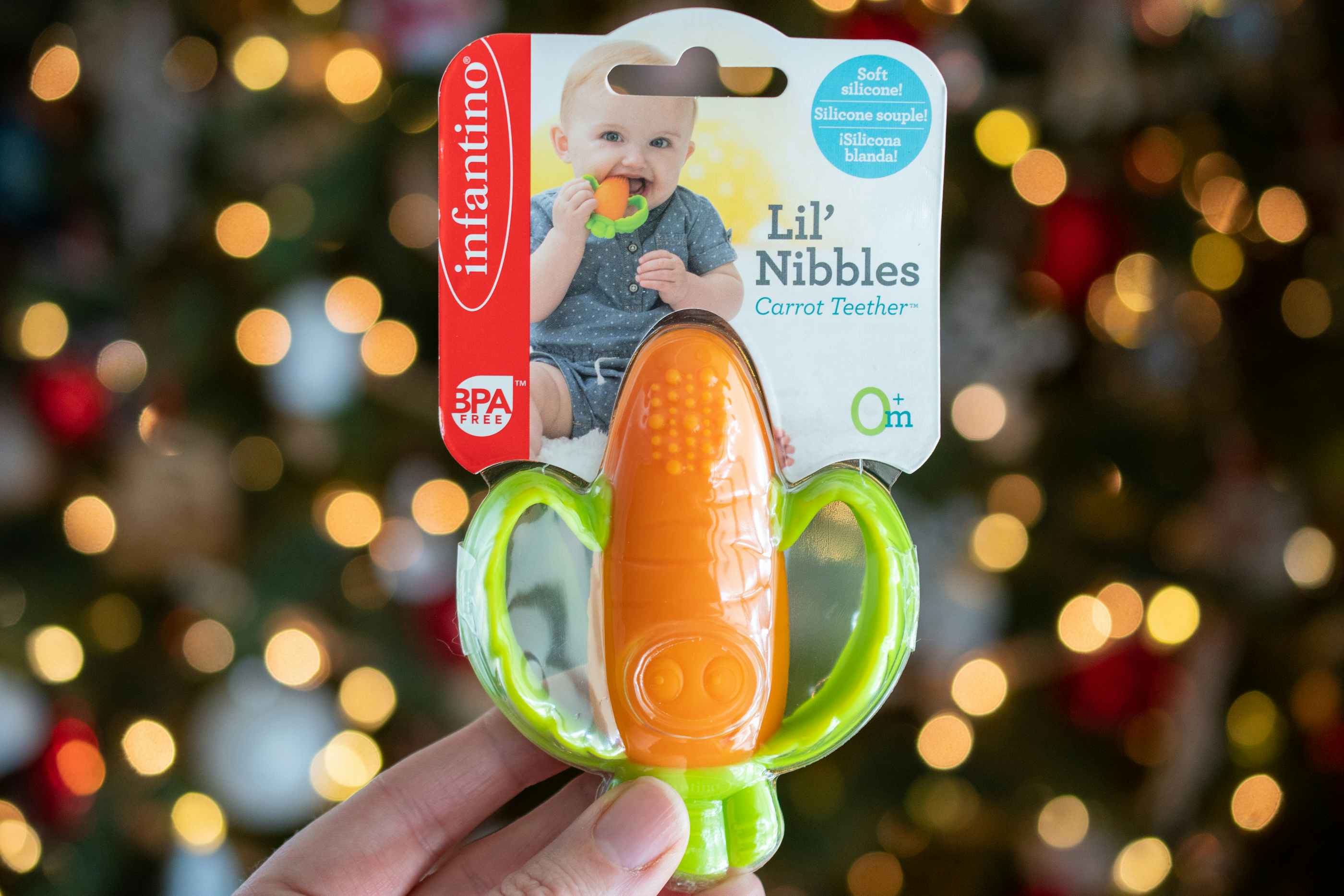 A person holding a baby teething toy shaped like a carrot