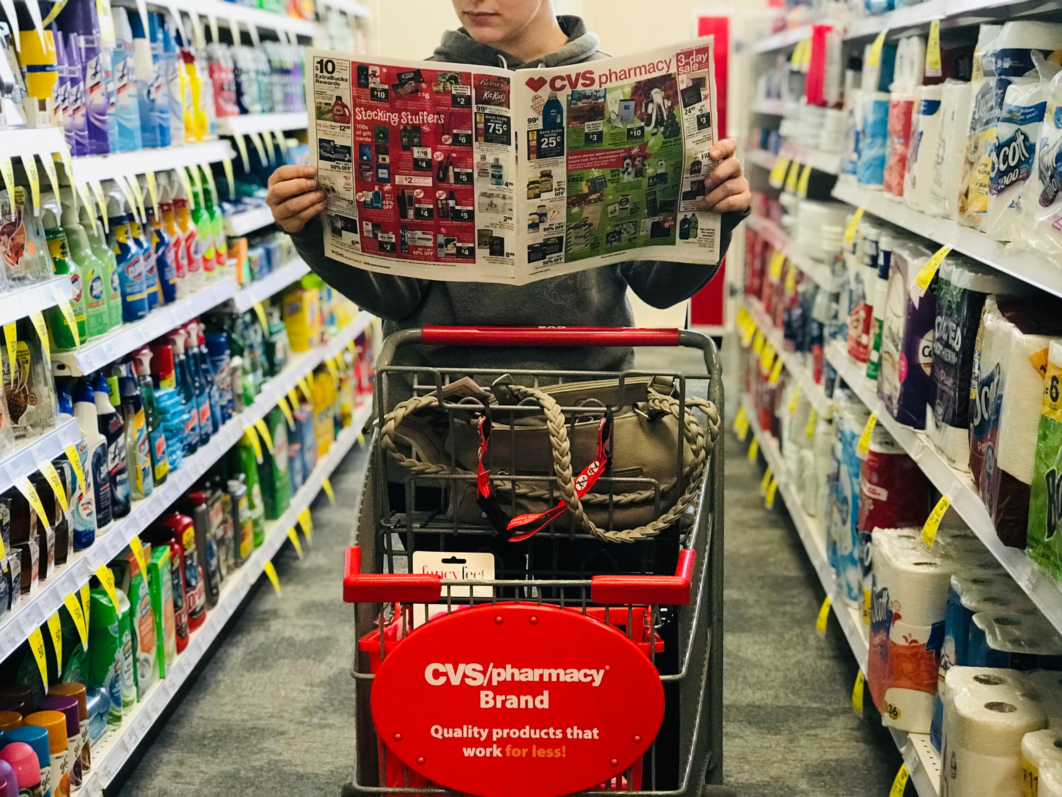 someone holding a cvs ad in front of a cvs cart