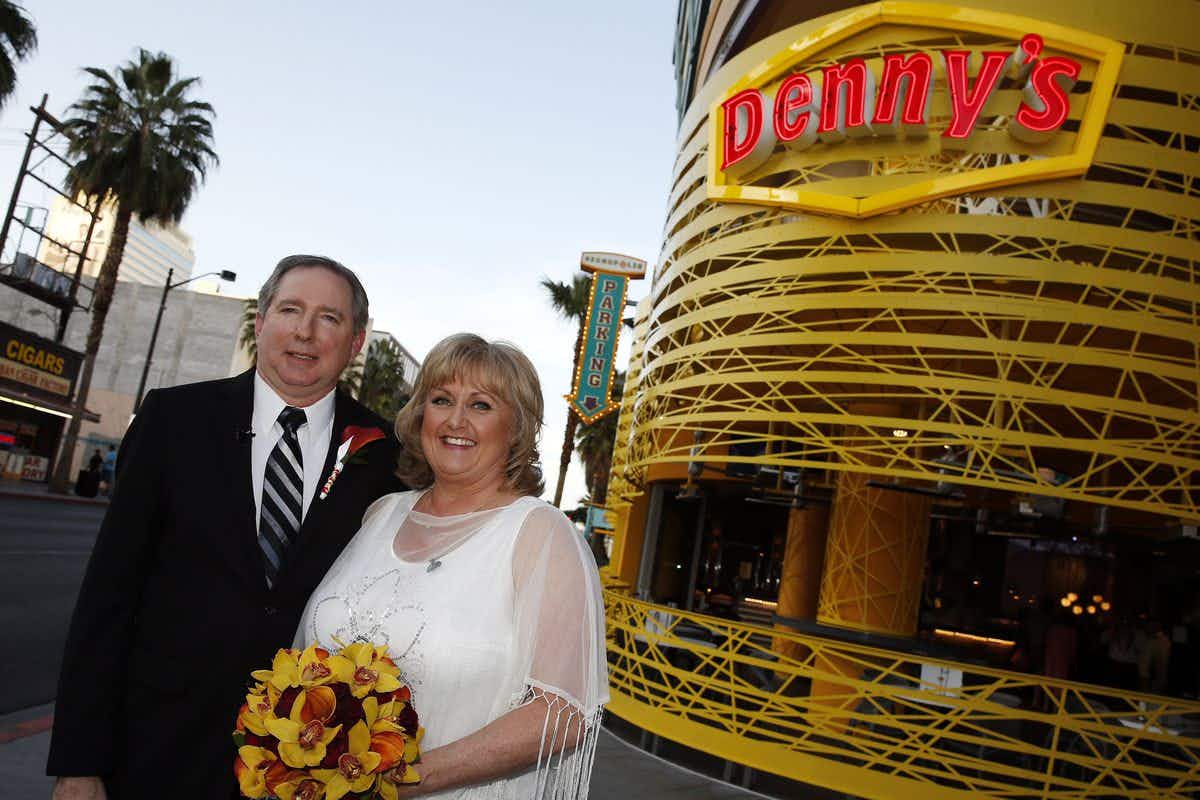 A bride and groom standing and smiling outside of the Denny's Chapel in Las Vegas, NV.