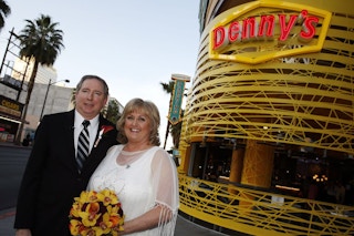A bride and groom standing and smiling outside of the Denny's Chapel in Las Vegas, NV.